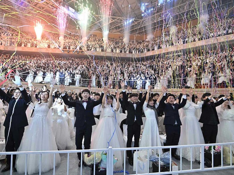 Couples cheer during a mass wedding ceremony organised by the Unification Church at Cheongshim Peace World Center in Gapyeong. Image Credit: AFP