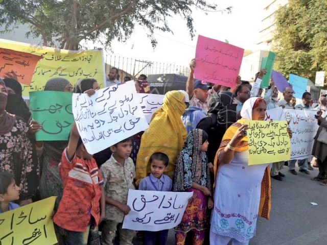 Women and children, affected by anti-encroachment operations on land allotted for the KCR, stand outside the Supreme Court’s Karachi Registry on Friday, demanding alternative housing before their residences are razed. PHOTO: PPI