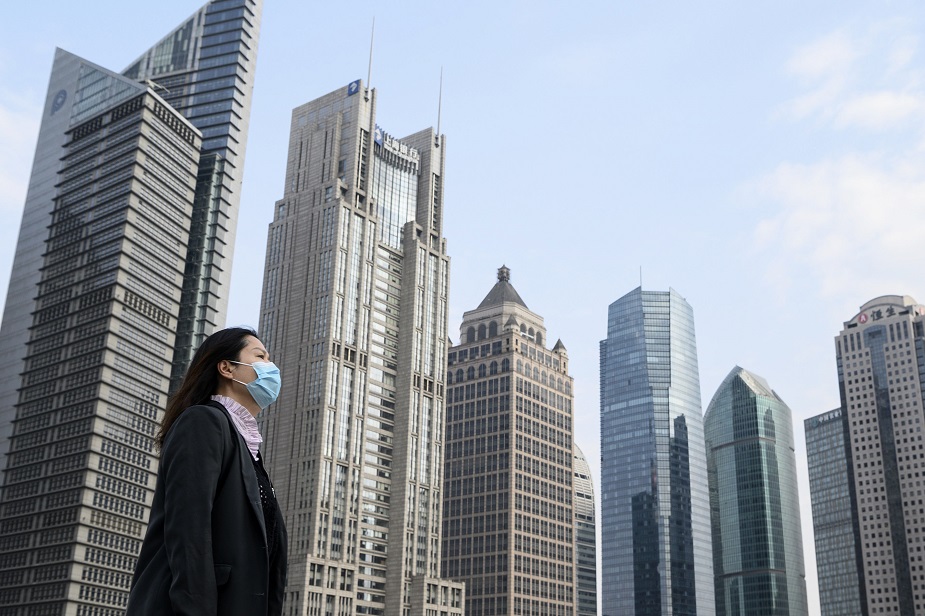 A woman wearing a protective face mask walks on an overpass in Shanghai on February 25, 2020. - China on February 25 reported another 71 deaths from the COVID-19 coronavirus, the lowest daily number of fatalities in over two weeks, which raised the toll to 2,663. PHOTO: AFP