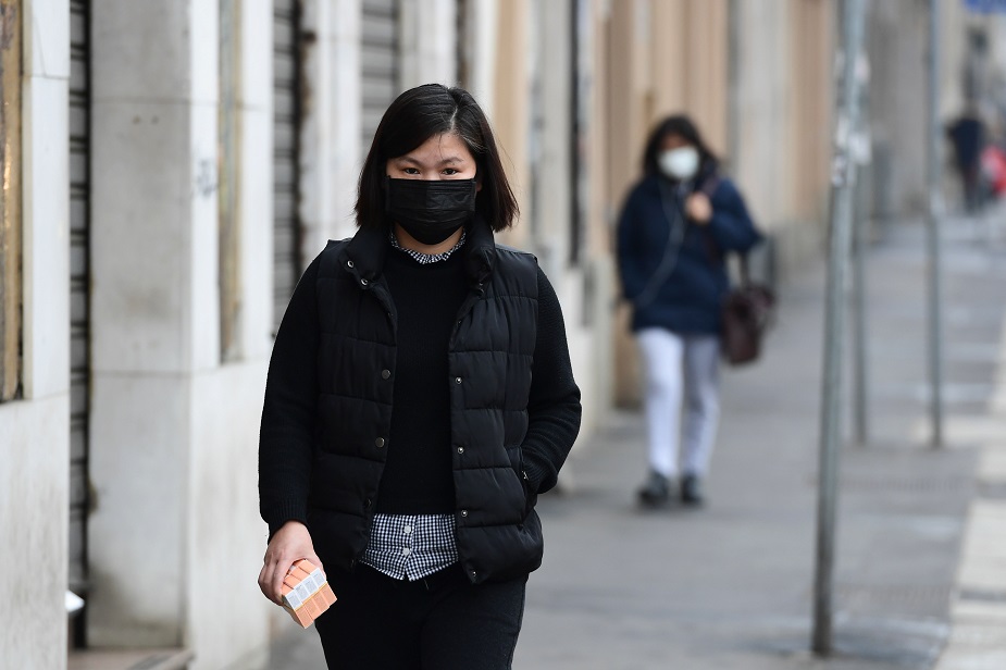 People wearing respiratory masks walk in a street of the Chinese district of Milan on February 25, 2020. - The decision to close the stores was made by the Chinese community of the city of Milan as a consequence of the current health situation, following the outbreak of the new coronavirus. Several towns in northern Italy have been put under isolation measures in an attempt to stem the spread of the virus. Seven people in Italy have so far died after catching the virus, all of whom were either elderly or had pre-existing conditions. PHOTO: AFP