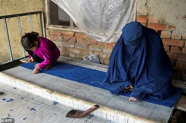 An Afghan refugee woman and her daughter make carpet at her home in a refugee camp in Peshawar. PHOTO: AFP