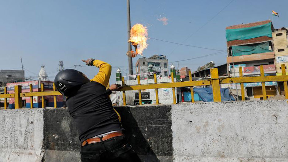 A man supporting a new citizenship law throws a petrol bomb at a Muslim shrine during a clash with those opposing the law in New Delhi, February 24. PHOTO: REUTERS