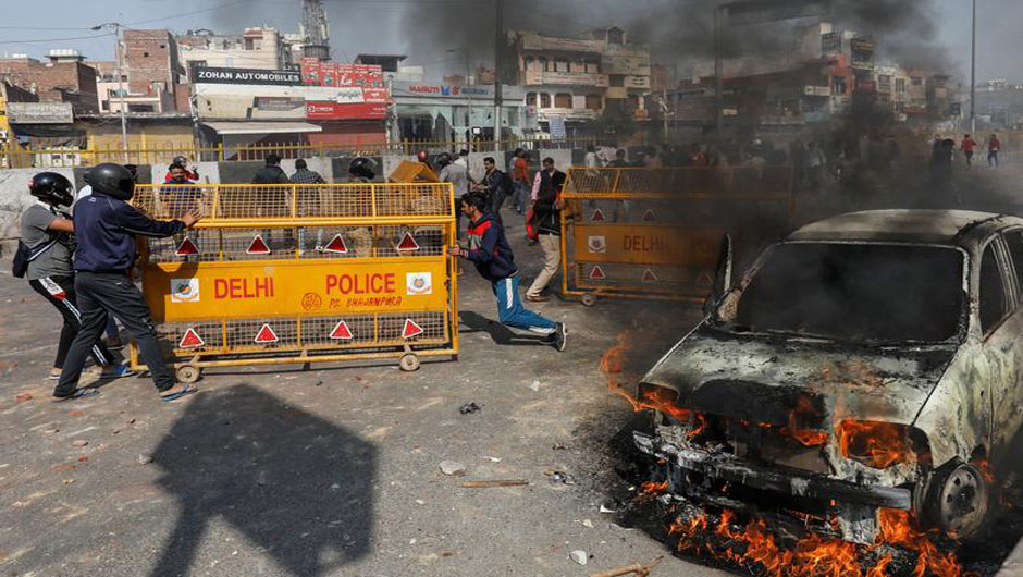 People supporting a new citizenship law push police barricades during a clash with those opposing the law in New Delhi, February 24. PHOTO: REUTERS