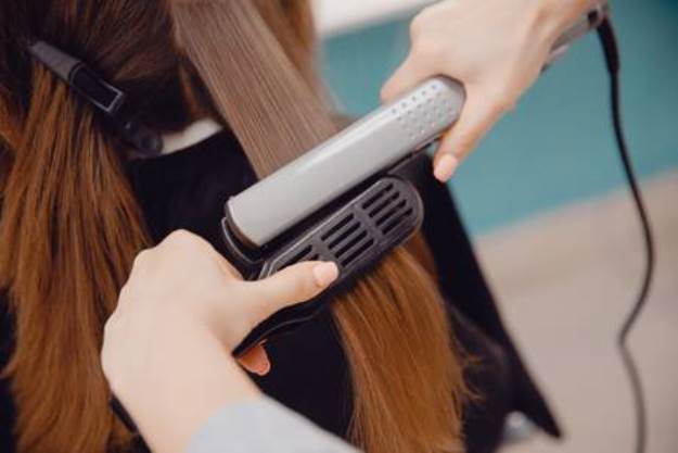 95997980-close-up-of-master-hairstylist-ironing-for-straightening-hair-restores-keratin-and-straightens-hair-