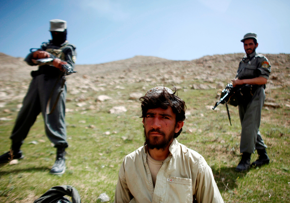 Afghan policemen stand next to a captured Taliban fighter after a gun battle near the village of Shajoy in Zabol province, Afghanistan March 22, 2008. PHOTO: REUTERS
