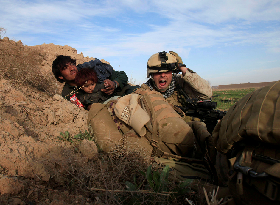 US Marine Lance Corporal Chris Sanderson, 24, from Flemington, New Jersey shouts as he tries to protect an Afghan man and his child after Taliban fighters opened fire in the town of Marjah, in Nad Ali district, Helmand province, Afghanistan February 13, 2010. PHOTO: REUTERS