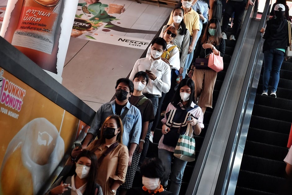 This photo shows people wearing protective facemasks, amid concerns of the COVID-19 coronavirus outbreak, as they ride on an escalator during the morning commute in Bangkok. PHOTO: AFP