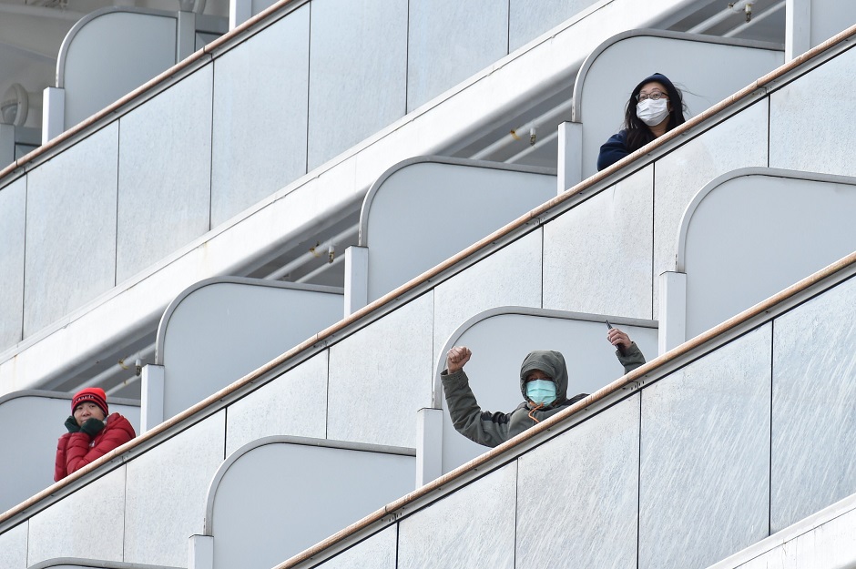 A passenger aboard the Diamond Princess cruise ship waves to the media upon arriving at Yokohama port. PHOTO: AFP