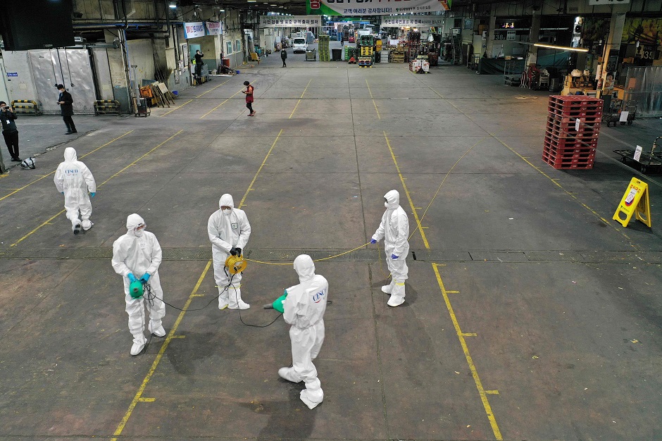 Workers from a disinfection service spray disinfectant as part of preventive measures against the spread of the COVID-19 coronavirus, at a fruit and vegetable market in Daegu. PHOTO: AFP