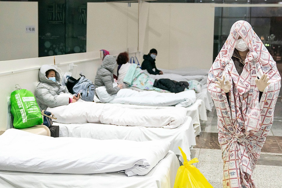 This photo shows a patient (R) covered with a bed sheet at an exhibition centre converted into a hospital as it starts to accept patients displaying mild symptoms of the novel coronavirus in Wuhan. PHOTO: AFP 