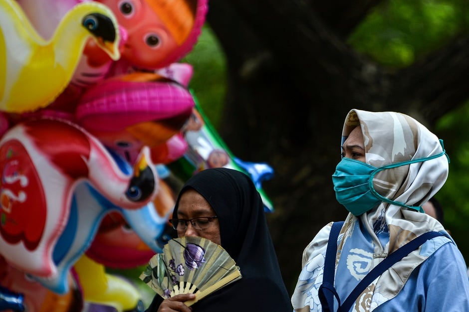 A woman (R) wears a face mask at a public area in Banda Aceh. PHOTO: AFP