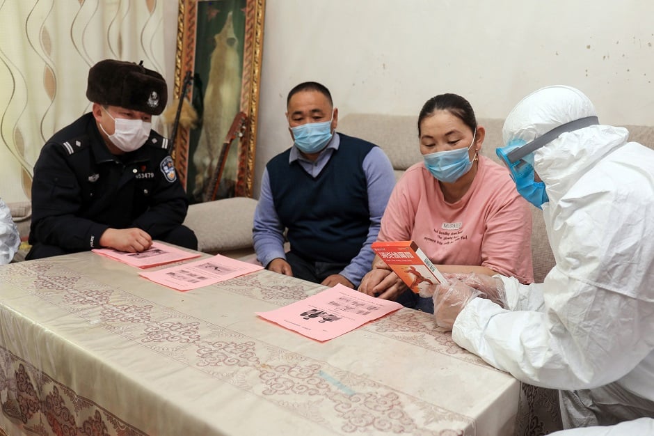 This photo shows police officers (L and R) visiting residents who live in remote areas in Altay, farwest China's Xinjiang region, to promote the awareness of the virus. PHOTO: AFP