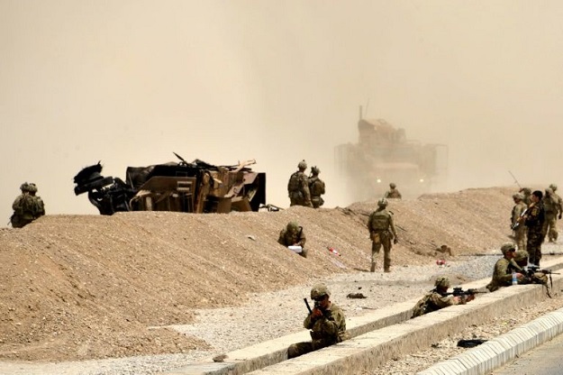US soldiers are seen here keeping watch near the wreckage of their vehicle at the site of a Taliban suicide attack in Kandahar in 2017. PHOTO: AFP 