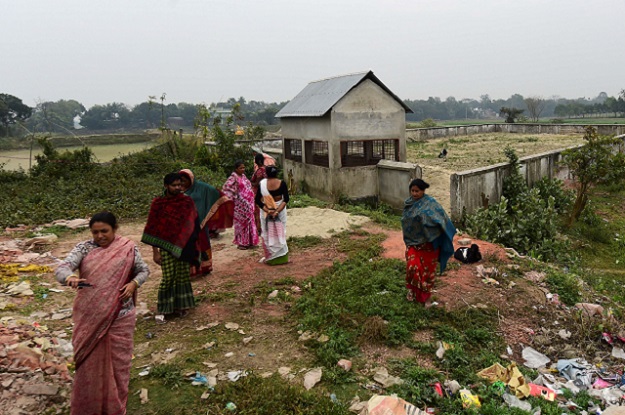 This photo shows Jhumur Begum (L), who heads a sex workers group, walking with other members next to a graveyard used for the burial of sex workers in Daulatdia. PHOTO: AFP