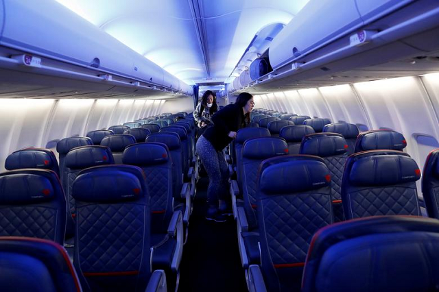 Air travellers grab carry-on luggage behind rows of empty seats aboard a flight, as coronavirus disruption continues across the global industry. PHOTO: Reuters