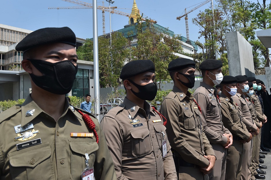 Police wearing facemasks, amid concerns over the spread of the COVID-19 novel coronavirus, stand guard outside the parliament building, currently under construction, as people take part in a demonstration calling for the creation of a new constitution in Bangkok on March 13, 2020.  PHOTO: AFP