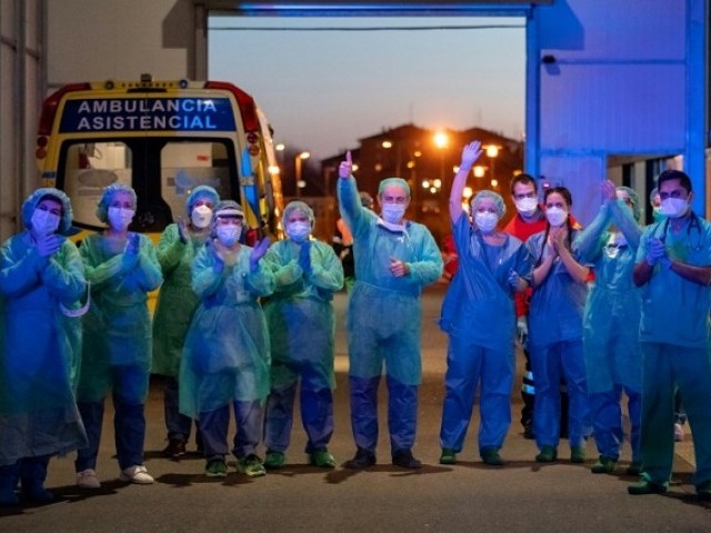 Healthcare workers dealing with the new coronavirus crisis applaud in return as they are cheered on by people outside a hospital in Burgos, Spain. PHOTO: AFP
