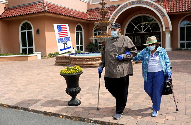 Rick Hatfield, 73, walks with his mother, Marie Rossi, 93, in face masks to protect themselves from coronavirus out of La Hacienda Recreation Center, as voters cast their ballots in the Democratic primary in The Villages, Florida. PHOTO: Reuters