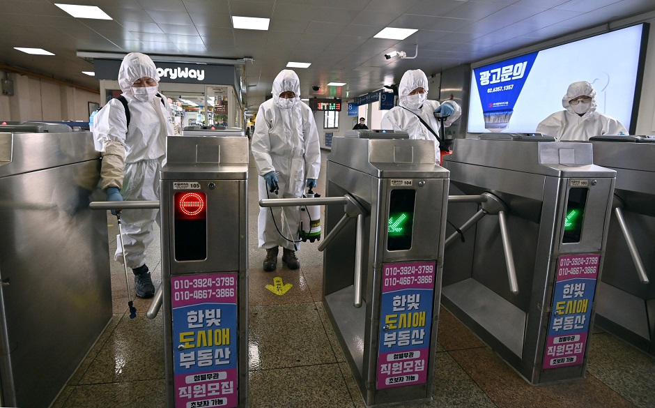 Workers wearing protective gear spray disinfectant to help prevent the spread of the COVID-19 coronavirus, at a subway station in Seoul on March 13, 2020. - South Korea -- once the largest coronavirus outbreak outside China -- saw its newly recovered patients exceed fresh infections for the first time on March 13, as it reported its lowest number of new cases for three weeks. The South confirmed 110 new cases taking the total to 7,979.  PHOTO: AFP