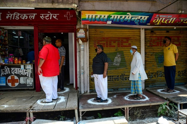 People stand on designated areas to maintain social distancing as they queue outside a medical store in Allahabad, India. PHOTO: AFP 