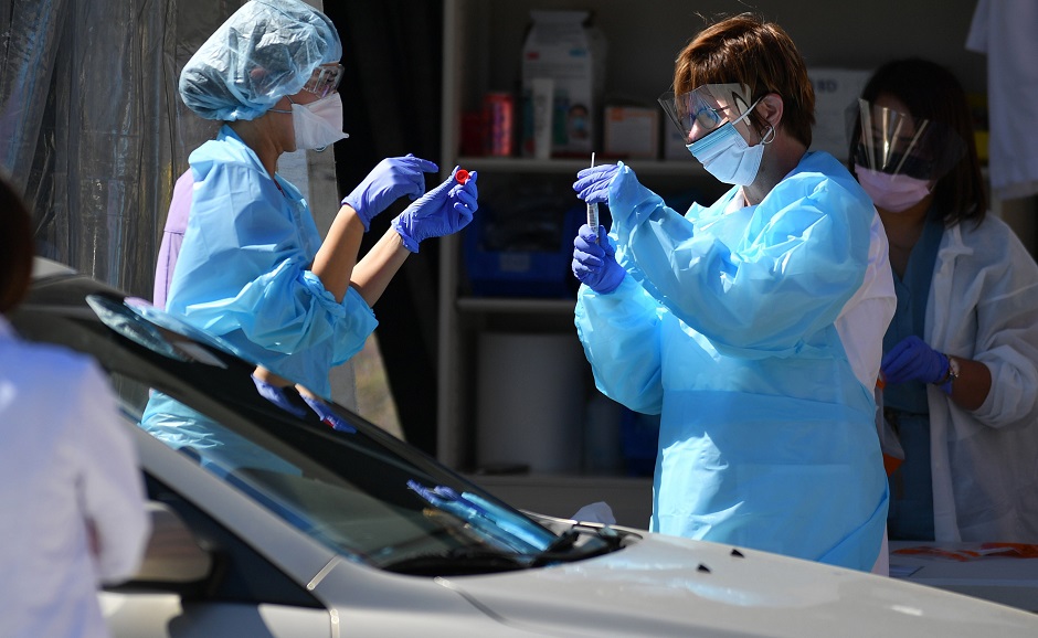 Medical workers at Kaiser Permanente French Campus test a patient for the novel coronavirus, COVID-19, at a drive-thru testing facility in San Francisco, California on March 12, 2020. - Between 70 to 150 million people in the United States could eventually be infected with the novel coronavirus, according to a projection shared with Congress, a lawmaker said March 12, 2020. PHOTO: AFP