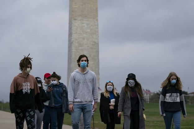 A group of young people wear protective masks as they walk near the Washington Monument on the National Mall. PHOTO: AFP 