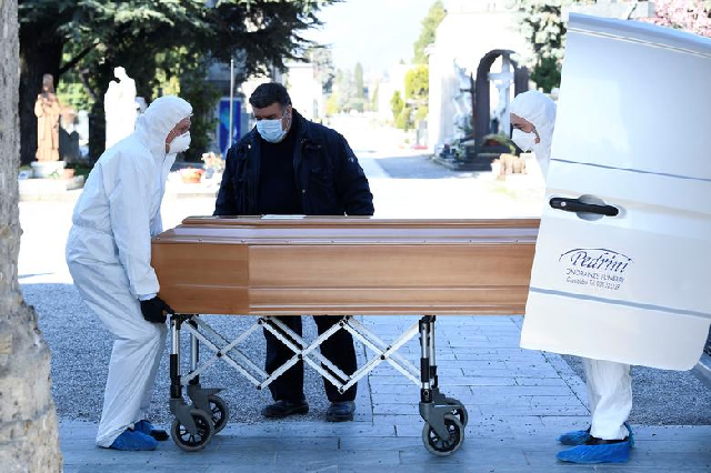 Men in protective masks transport a coffin of a person who died from coronavirus into a cemetery in Bergamo, Italy. PHOTO: Reuters