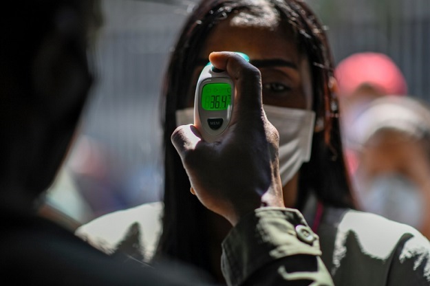 A member of the Bolivarian National Guard checks a woman's temperature outside a market in Caracas, Venezuela on March 20, 2020. PHOTO: AFP 