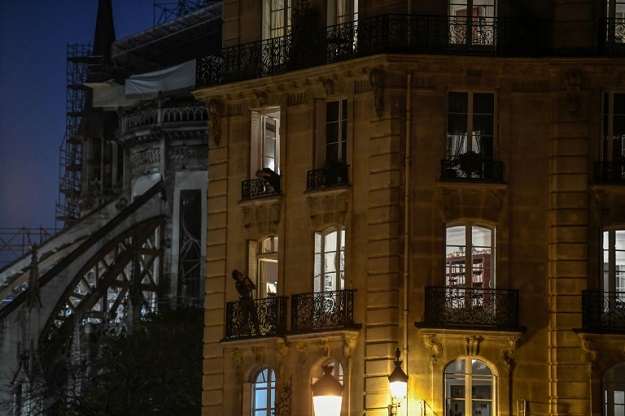 Neighbourgs talk to each other from their balconies in in Isle Saint-Louis in Paris, on the ninth day of the lockdown in France. PHOTO: AFP 