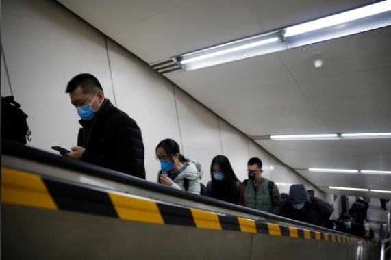 People wearing masks ride an escalator as they exit a subway station. PHOTO: REUTERS