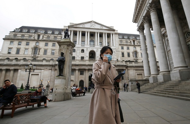 A woman, wearing a protective face mask, walks in front of the Bank of England, following an outbreak of the coronavirus in London. PHOTO: Reuters