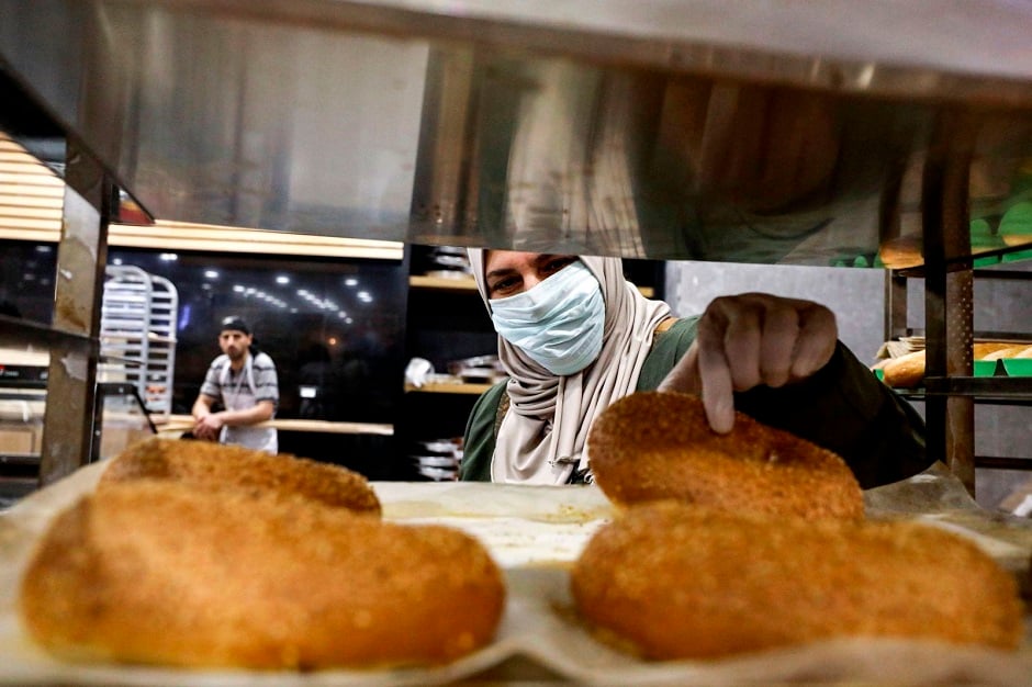 A woman in Hebron, West Bank, picks out freshly baked pastries as she shops for groceries before the start of Ramadan. PHOTO: AFP