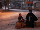 A woman and a girl sit on a deserted road as they sell handmade masks during the Muslim fasting month of Ramadan, amid lockdown in efforts to stem the spread of the coronavirus disease (COVID-19), in Karachi, Pakistan April 28, 2020. REUTERS