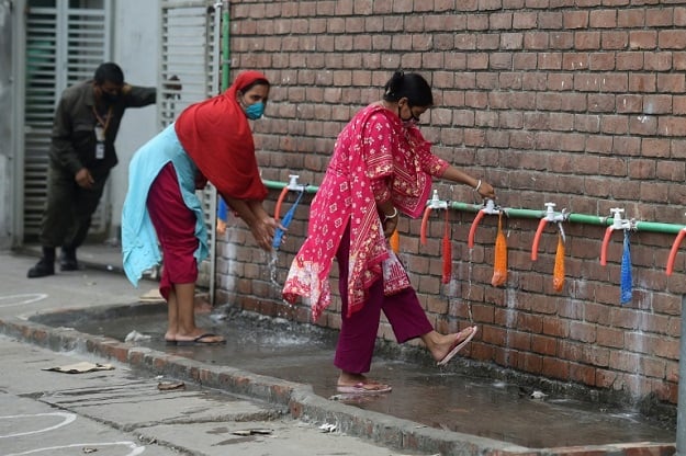 Garment workers wash their legs before entering a factory in Dhaka, Bangladesh, where hundreds of such factories reopened despite a nationwide lockdown against new coronavirus. PHOTO: AFP