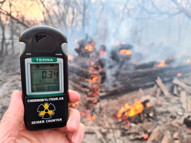 A geiger counter measures a radiation level at a site of fire burning in the exclusion zone around the Chernobyl nuclear power plant, outside the village of Rahivka, Ukraine. Photo: Reuters 