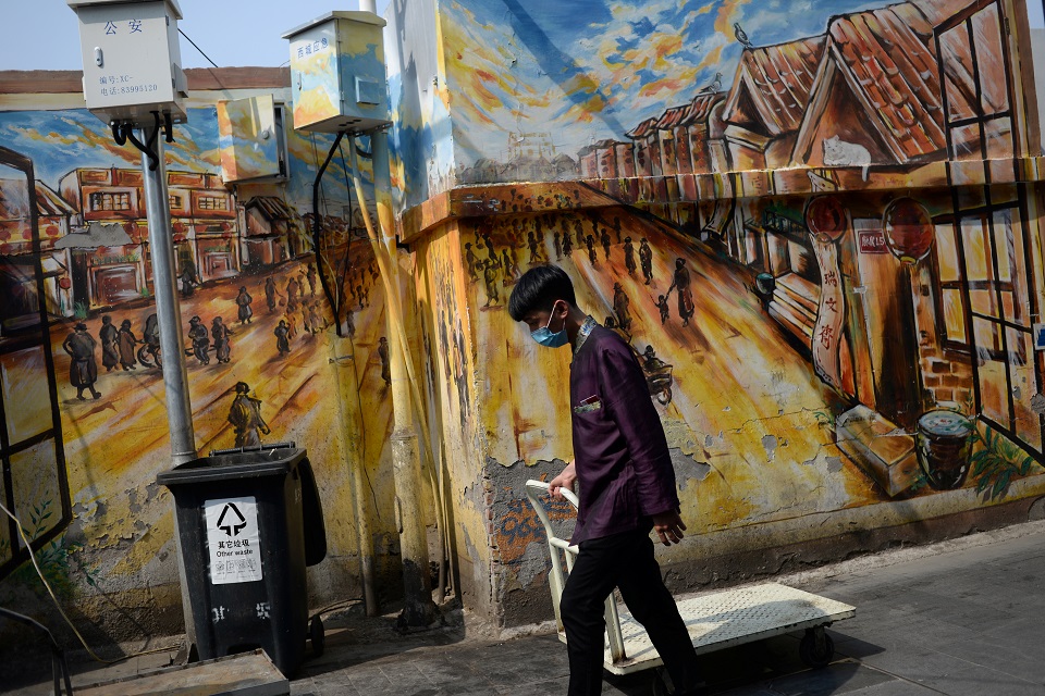 A worker wearing a face mask pulls a cart past a painted wall near the Qianmen street, on the first day of the five-day Labour Day holiday following the coronavirus disease (COVID-19) outbreak, in Beijing, China May 1, 2020. REUTERS/Tingshu Wang