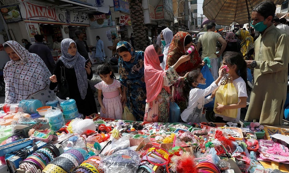 Women and children shop from a stall in a market, after Pakistan started easing the lockdown as the coronavirus disease (COVID-19) continues, in Karachi, Pakistan May 11, 2020. REUTERS/Akhtar Soomro