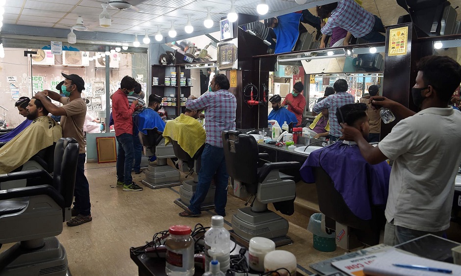 Barbers give haircuts to customers after the government eased the nationwide lockdown imposed as a preventive measure against the COVID-19 coronavirus, in Rawalpindi on May 11, 2020. (Photo by Farooq NAEEM / AFP)