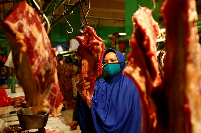 A woman wears a protective face mask as she buys meat for making traditional food ahead of Eidul Fitr celebrations at the traditional market in Jakarta, Indonesia. PHOTO: Reuters