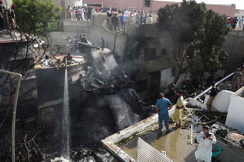 Firefighters spray water on the wreckage. PHOTO: AFP