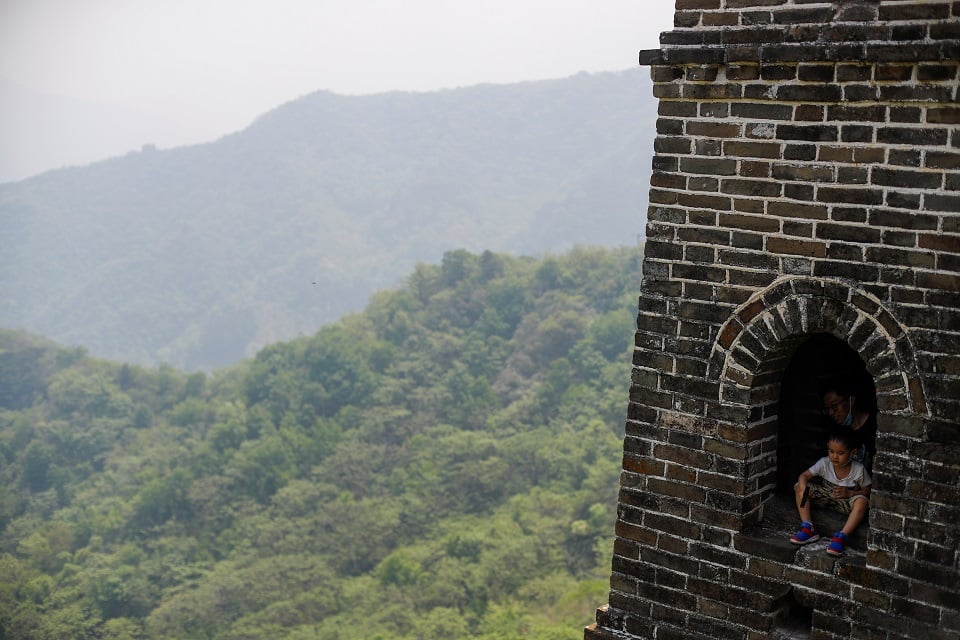 A boy sits in a window of a watchtower while visiting the Mutianyu section of the Great Wall of China on the first day of the five-day Labour Day holiday following the coronavirus disease (COVID-19) outbreak, on the outskirts of Beijing, China May 1, 2020. REUTERS/Thomas Peter
