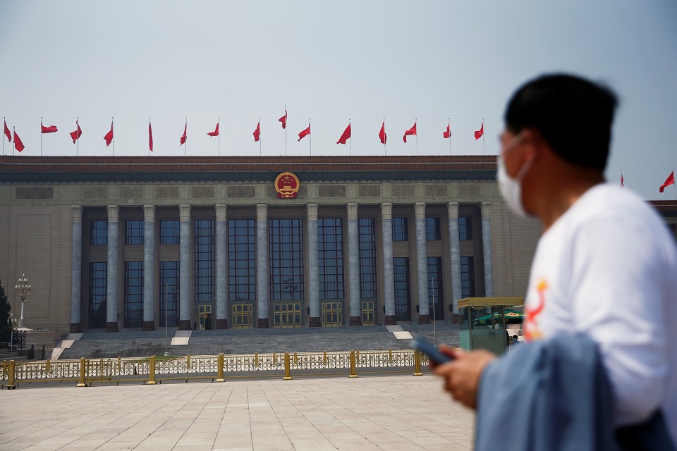 A man wearing a face mask walks on Tiananmen Square in front of the Great Hall of the People following the coronavirus disease (COVID-19) outbreak, during the Labour-Day holiday in Beijing, China May 1, 2020. REUTERS/Tingshu Wang