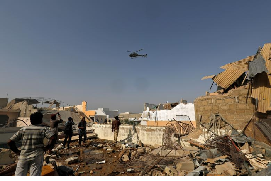 A chopper flies over the site of a passenger plane crash in a residential area near an airport in Karachi. PHOTO: REUTERS