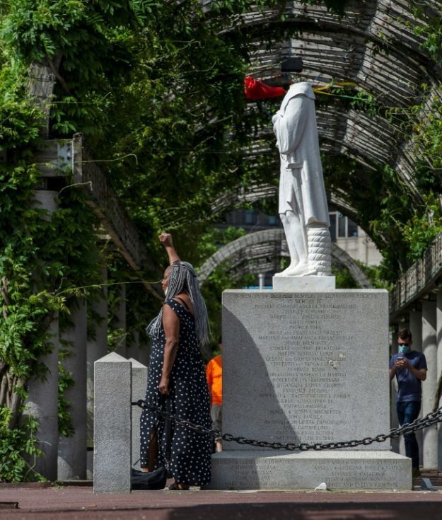A woman poses in front of a decapitated statue of Columbus at Christopher Columbus Park in Boston, Massachusetts on June 10. PHOTO: AFP