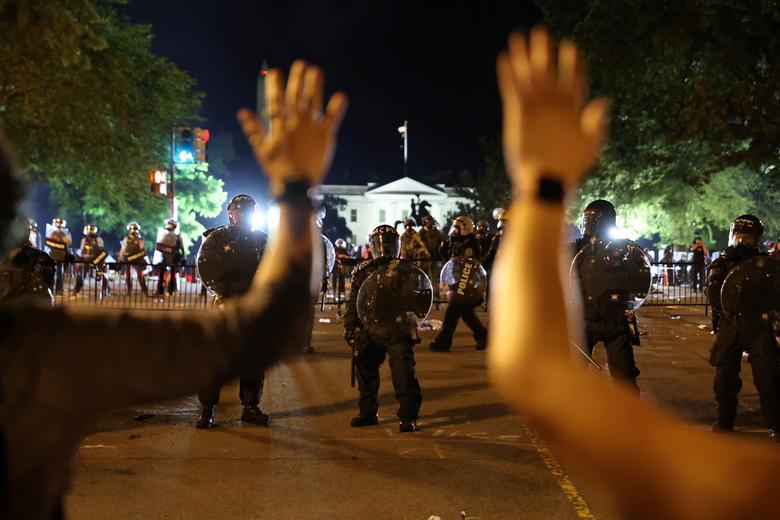 Protesters hold their hands up in front of law enforcement personnel as demonstrators rally at the White House. Photo: Reuters
