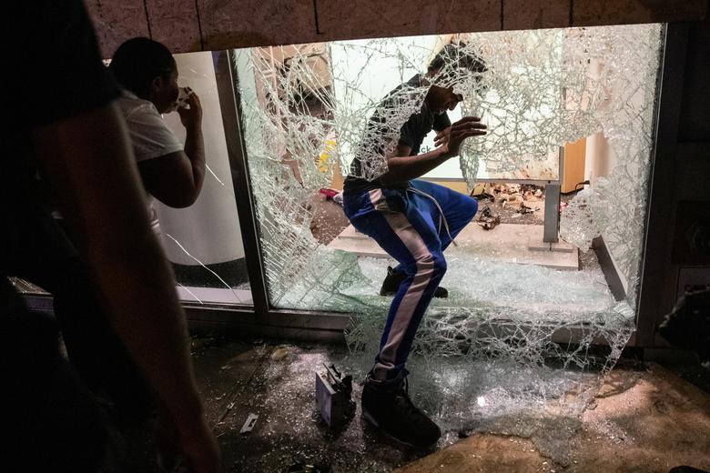 People climb into a damaged store during a protest against the death in Minneapolis police custody of George Floyd, in Manhattan, New York, June 1. REUTERS