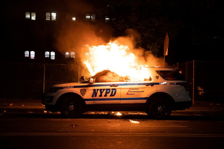 A NYPD police car is set on fire as protesters clash with police during a march against the death in Minneapolis police custody of George Floyd, in the Brooklyn borough of New York City, May 30, 2020. REUTERS