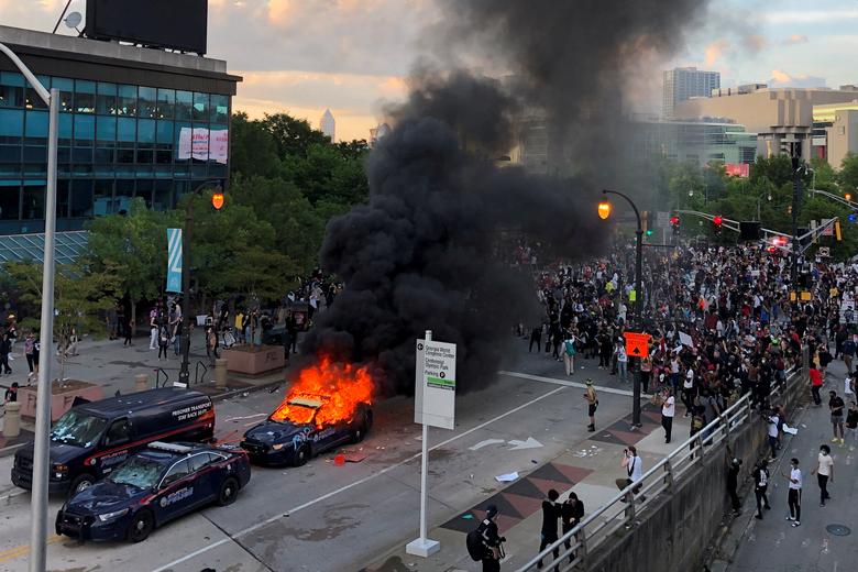 An Atlanta Police car burns as people protest near the CNN Center in Atlanta, Georgia, May 29, 2020. REUTERS